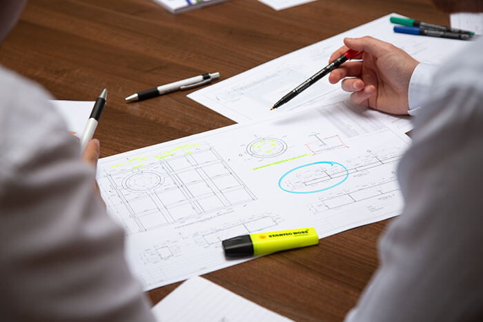 2 men looking at drawings on a desk